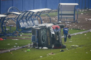 Indonesia demolerá el estadio de fútbol donde una estampida dejó más de 130 muertos 
INDONESIA FÚTBOL: MALANG, 02/10/2022.- Una mujer pasa junto a un vehículo de la policía destrozado tras los disturbios en un partido de fútbol en el estadio Kanjuruhan de Malang, que han dejado al menos 174 muertos. El brote de violencia se produjo después de que cerca de 3.000 aficionados del equipo Arema irrumpieran en el campo tras la derrota 2-3 sufrida ante el rival Persebaya Surabaya y chocaran con las fuerzas de seguridad, que a su vez utilizaron gases lacrimógenos en un intento de dispersar la multitud. EFE/ Sandi Sadewa