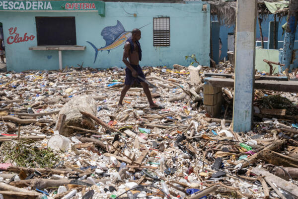Un hombre camina por la playa Manresa, cubierta de basura tras el paso del huracán Beryl