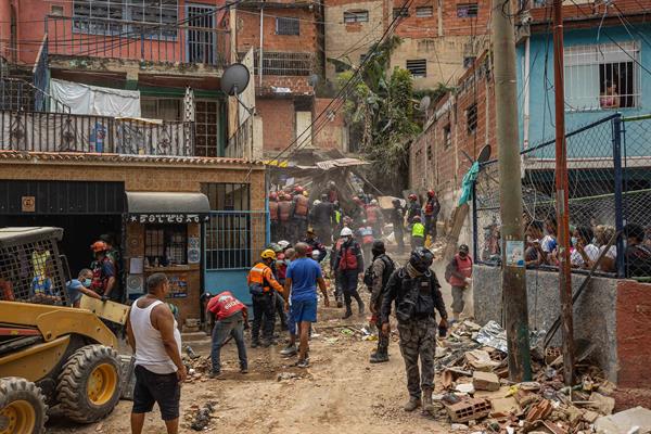 Rescatistas trabajan en la zona donde se derrumbó un edificio de tres pisos este lunes, en el barrio Unión de Petare en Caracas (Venezuela). EFE