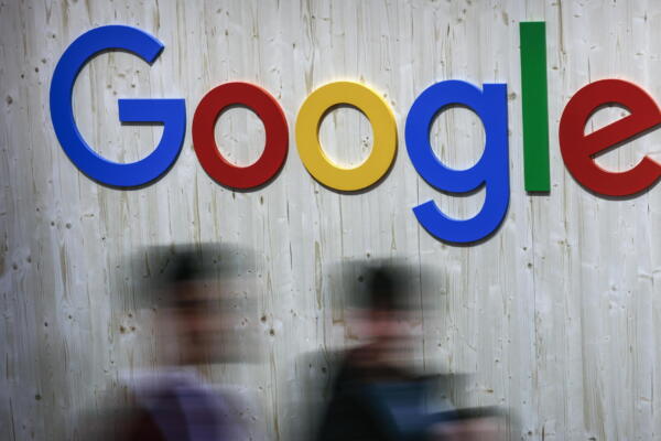 Fotografía de archivo en donde personas pasan frente a un letreto de Google