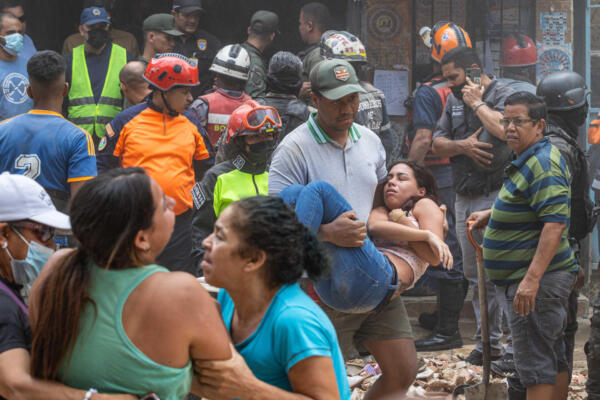 Un hombre carga a una mujer en la zona donde se derrumbó un edificio de tres pisos este lunes, en el barrio Unión de Petare en Caracas 