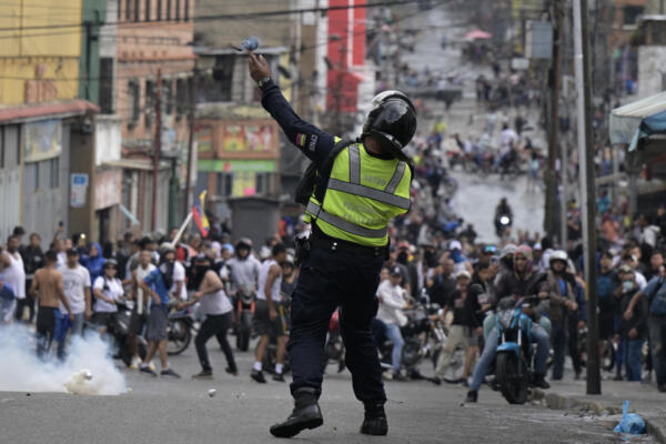 Un oficial de la policía antidisturbios utiliza gases lacrimógenos contra manifestantes durante una protesta de opositores al gobierno de Maduro. (Foto de Yuri CORTEZ / AFP)