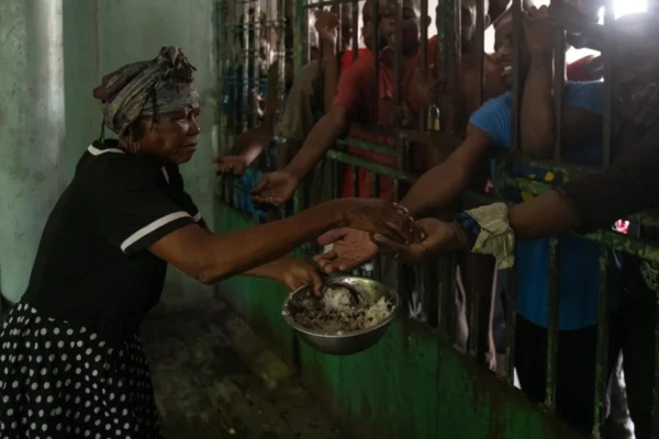 Señora les ofrece comida a hombres en el centro psiquiátrico Mars & Kline, en Puerto Príncipe (Haití). EFE.