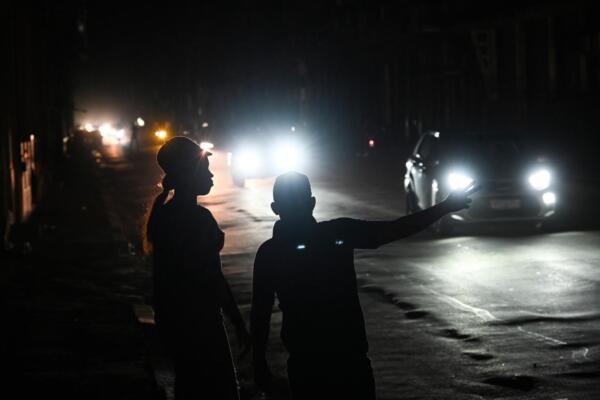 La gente espera un taxi en una calle durante la tercera noche de un apagón nacional en La Habana el 20 de octubre de 2024. (Foto de YAMIL LAGE / AFP)