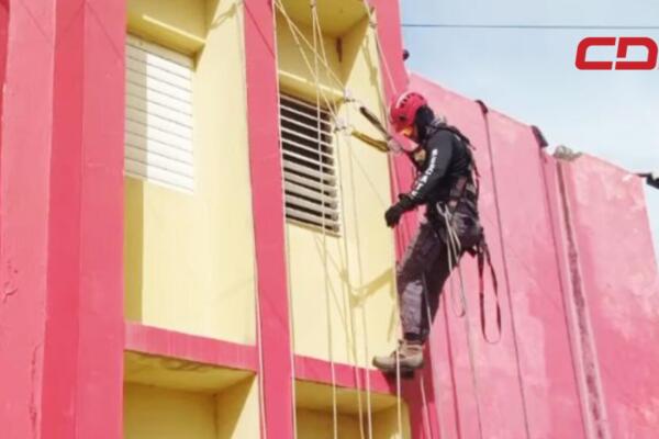 Bombero recibiendo entrenamiento en rescate vertical en altura.