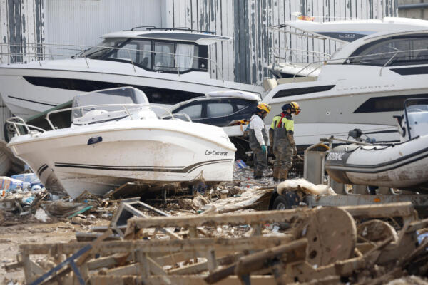 Dos bomberos inspeccionan las inmediaciones de una empresa con lanchas marinas en Massanassa, este miércoles. 