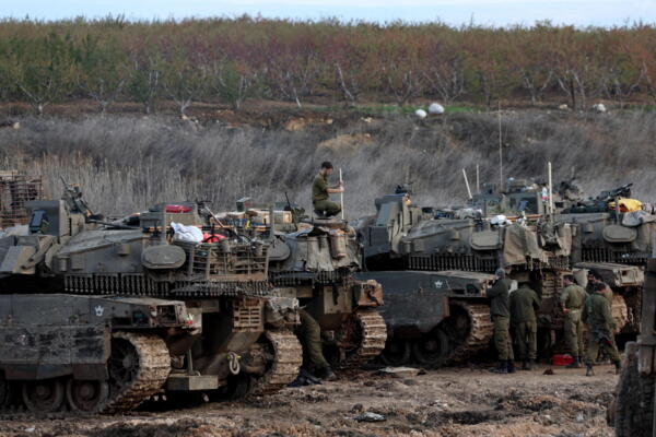 Soldados israelíes pasan junto a tanques estacionados en un campo al regresar a Israel tras un alto el fuego con HizbuláSAFADI