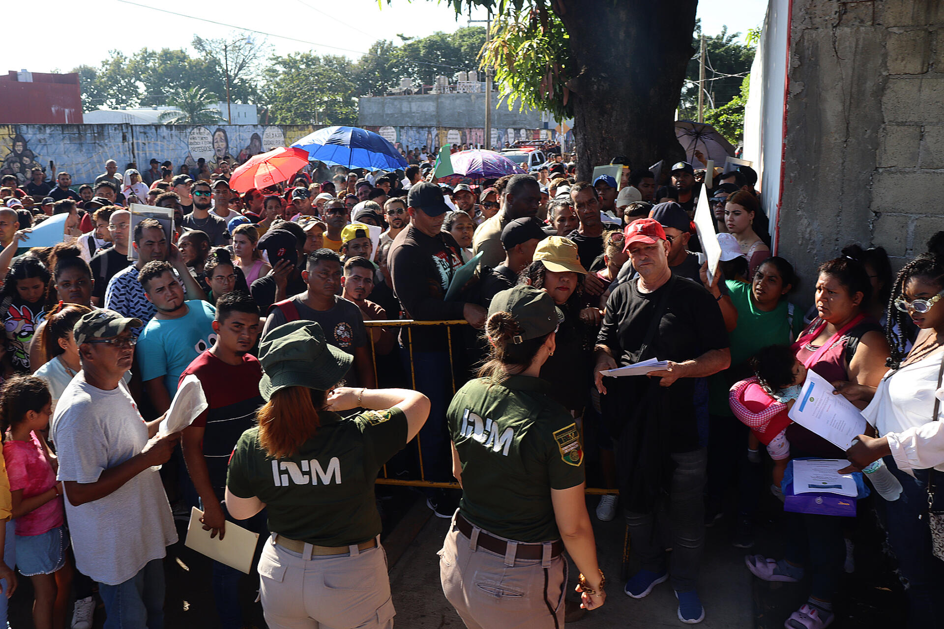 Personal del Instituto Nacional de Migración (INM) hablan con migrantes que esperan resolver su situación migratoria