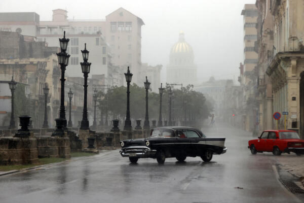 Automóviles transitan por una calle durante las fuertes lluvias debido al paso del huracán Rafael. EFE