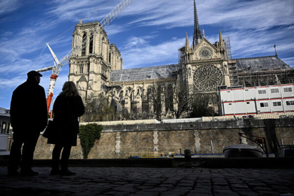 Los peatones miran la catedral de Notre-Dame de París rodeada por barreras y vallas de seguridad en la víspera de su reapertura oficial  (Foto de JULIEN DE ROSA / AFP)