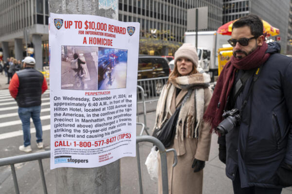 Personas leen un cartel de recompensa para quien ayude en la captura del asesino del director ejecutivo de la aseguradora UnitedHealthcare