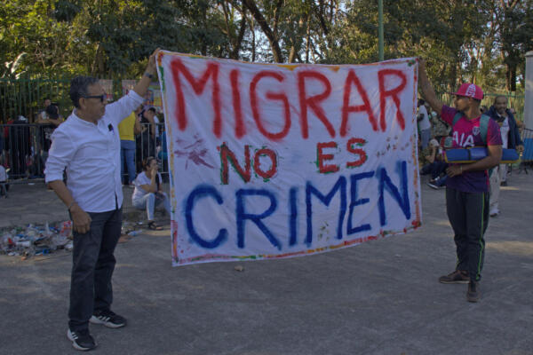 Fotografía de archivo en donde se ven migrantes que sostienen un cartel. 