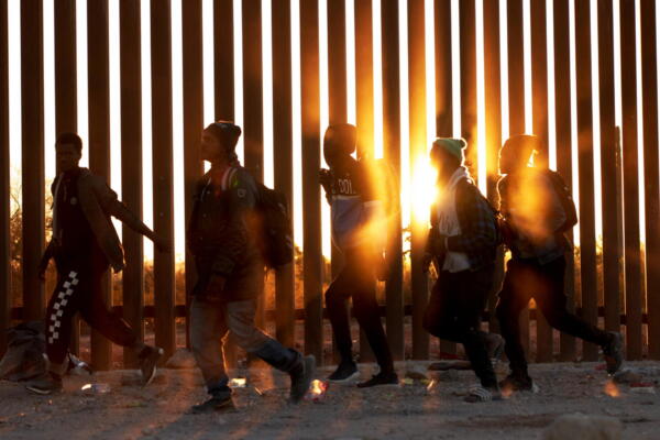 Fotografía de migrantes que caminan junto al muro en la frontera de EE.UU, y México, en Lukeville, Arizona. 
EFE/ Allison Dinner