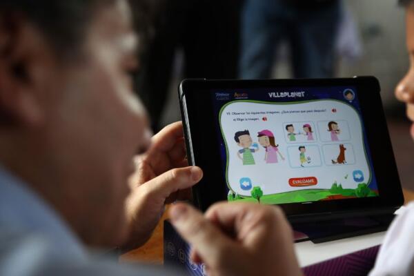 Fotografía de una persona junto a un niño manipulando una tableta en un colegio. 
EFE/ Paolo Aguilar