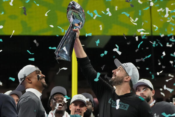 El mariscal de campo #01 de los Philadelphia Eagles, Jalen Hurts, sonríe mientras el entrenador en jefe de los Philadelphia Eagles, Nick Sirianni, sostiene el trofeo Lombardi después de derrotar a los Kansas City Chiefs 40-22 en el Super Bowl LIX en el Caesars Superdome de Nueva Orleans, Luisiana, el 9 de febrero de 2025. (Foto de TIMOTHY A. CLARY / AFP)