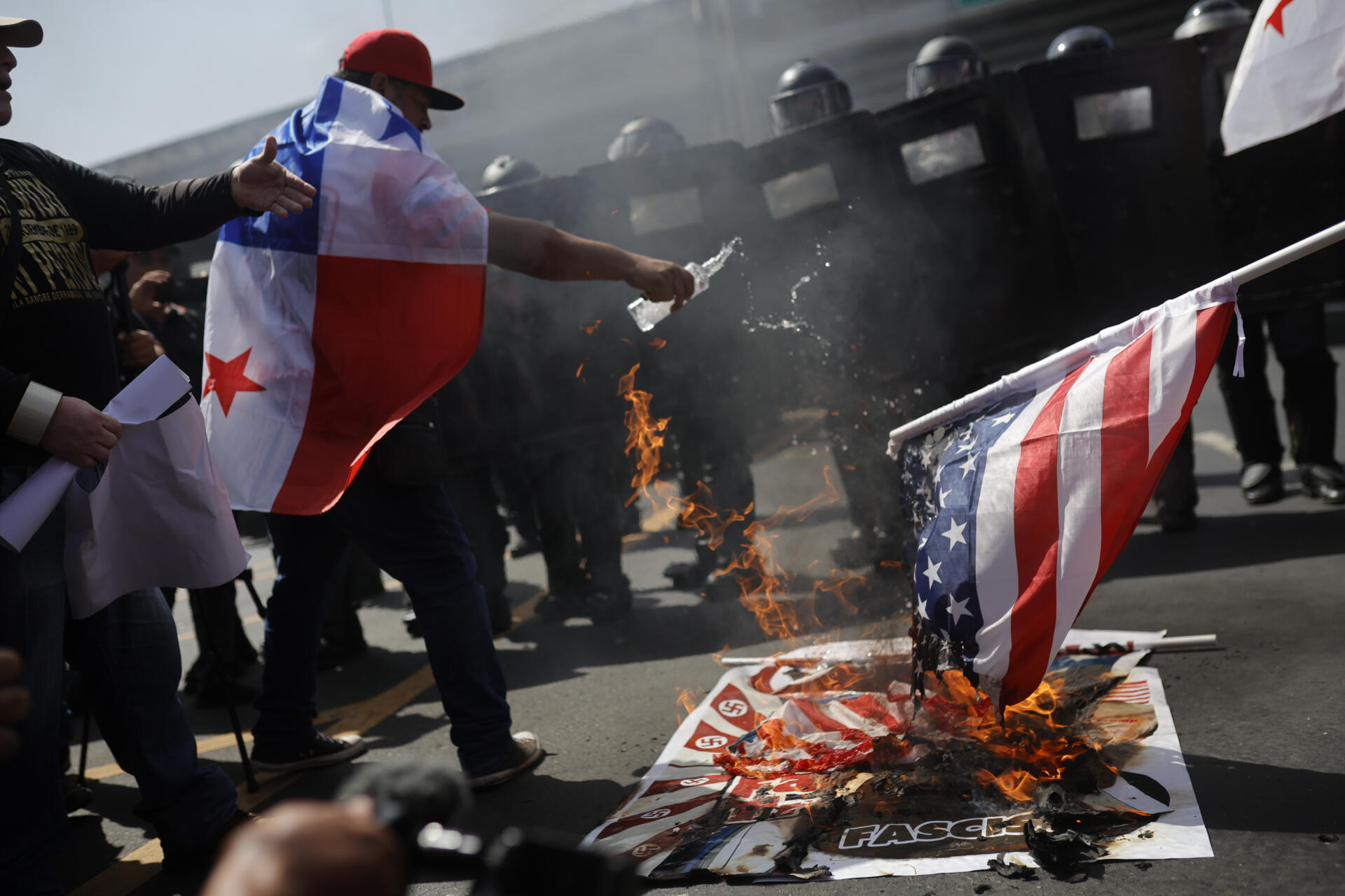 Personas queman una bandera de Estados Unidos durante una protesta por la visita del Secretario de Estado de Estados Unidos, Marco Rubio