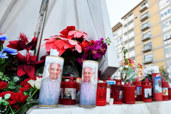 Flores y velas colocadas al pie de una estatua del papa San Juan Pablo II frente al Hospital Universitario Gemelli, donde el papa Francisco está ingresado, en Roma, el 21 de febrero de 2025. EFE/EPA/FABIO CIMAGLIA