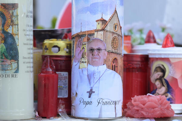 Se colocan velas ante la estatua de Juan Pablo II frente al Hospital Universitario Gemelli, donde el Papa Francisco está hospitalizado con neumonía, en Roma el 2 de marzo de 2025.  (Foto de Tiziana FABI / AFP)