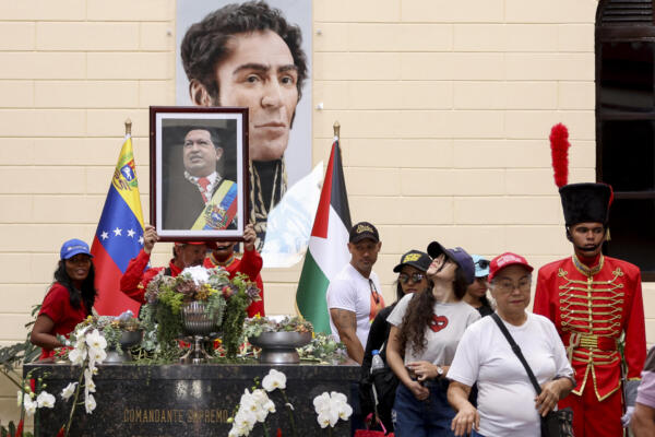 La gente presenta sus respetos ante la tumba del fallecido presidente venezolano Hugo Chávez durante una marcha conmemorativa del 12º aniversario de su muerte en el Cuartel Montana 4F, donde están enterrados sus restos en Caracas el 5 de marzo de 2025. (Foto de Pedro MATTEY / AFP)
