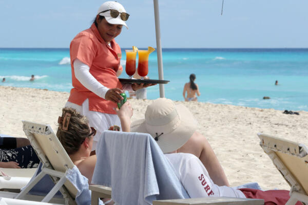 Personal de complejos hoteleros atienden a turistas en una playa del balneario de Cancún en Quintana Roo (México). EFE/ Alonso Cupul