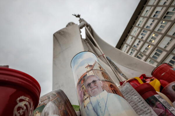 Velas con imágenes del Papa Francisco en la base de una estatua del Papa San Juan Pablo II frente al Hospital Universitario Gemelli en Roma, Italia. EFE/EPA/GIUSEPPE LAMI