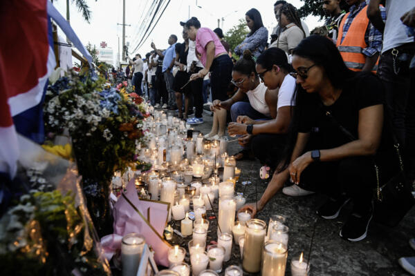 Familiares y amigos encienden velas para rendir homenaje a las víctimas frente a la discoteca Jet Set en Santo Domingo el 12 de abril de 2025.  (Foto de Eddy Vittini / AFP)