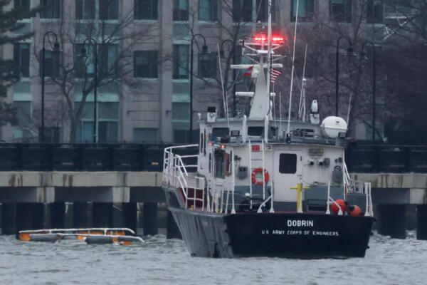 Los patines de aterrizaje de un helicóptero (izq.) se ven en el agua junto a una embarcación del Cuerpo de Ingenieros del Ejército de EE. UU. frente a la costa de Hoboken, tras estrellarse en el río Hudson. AFP