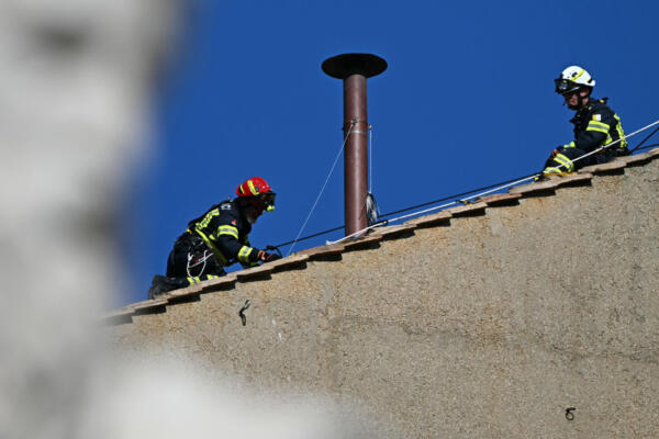Obreros instalan la chimenea en el tejado de la Capilla Sixtina, con la estatua de San Pablo en primer plano, en el Vaticano, el 2 de mayo de 2025. El cónclave comienza el 7 de mayo, cuando un número récord de 133 cardenales (menores de 80 años con derecho a voto) entrarán en la Capilla Sixtina para votar en secreto por un nuevo pontífice. (Foto de Gabriel BOUYS / AFP)
