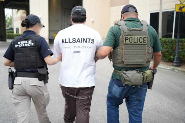 Agentes de la policía trasladando a un inmigrante detenido durante la operación 'Marea Negra' este jueves, en Miami. EFE