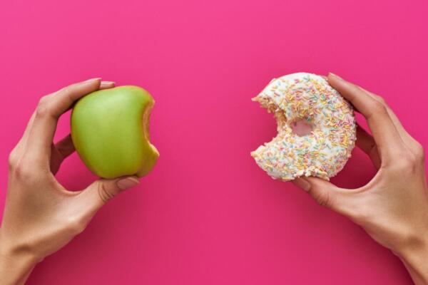 Una persona sosteniendo una manzana y una donat. Foto: Fuente externa 