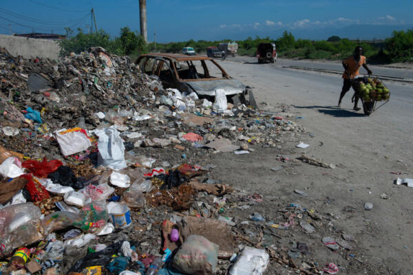 Un hombre camina con sus plátanos cerca de un montón de basura en Puerto Príncipe, Haití, el 24 de mayo de 2025. AFP