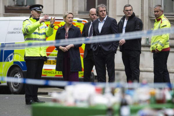 La ministra del Interior británica, Yvette Cooper (2.ª izq.), reacciona mientras escucha al subjefe de policía Chris Green (izq.) durante una visita al lugar del incidente en Water Street, Liverpool. AFP