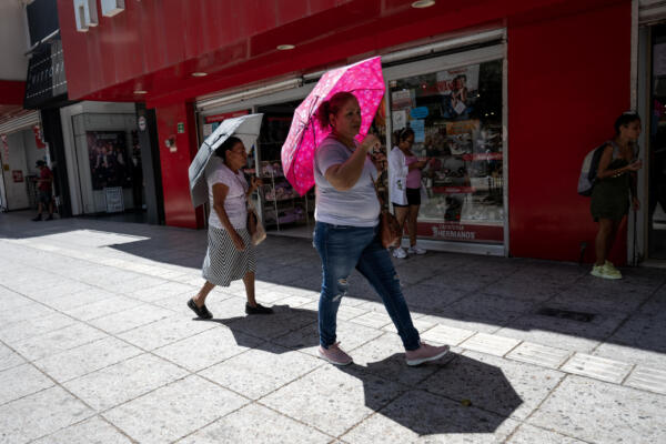 Imagen de mujeres que sostienen sombrillas para protegerse del sol en la ciudad de Monterrey (México). EFE