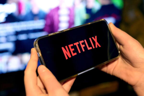 Fotografía en donde una persona sostiene en sus manos un teléfono con la aplicación de Netflix. EFE