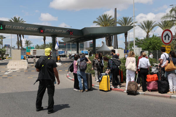 Viajeros esperan junto a sus equipajes en el exterior del aeropuerto Ben Gurión de Israel, mientras los vuelos se interrumpen tras la activación de las defensas aéreas contra un misil lanzado desde Yemen. AFP