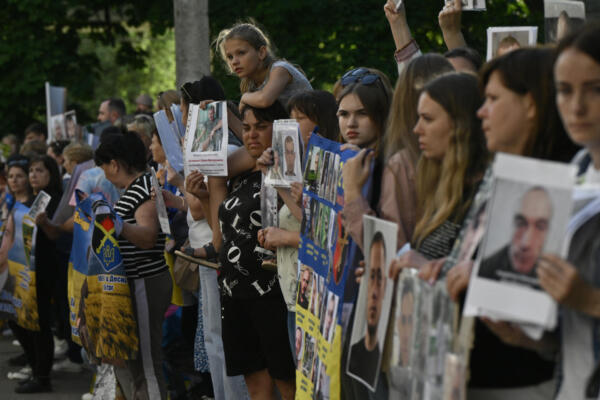 Personas sostienen retratos de sus familiares y amigos desaparecidos o capturados mientras esperan la llegada de los prisioneros de guerra ucranianos liberados a la región de Chernigiv el 23 de mayo de 2025, en medio de la invasión rusa de Ucrania. AFP