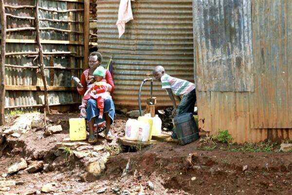 Una mujer y sus dos hijos recogen agua en bidones en uno de los distritos de Kibera (Kenia). Foto: EFE
