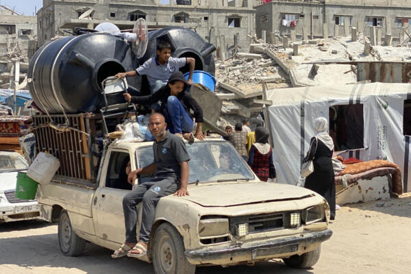 Boys sit with large water cisterns, a fan, and other furniture atop a moving vehicle as displaced people flee from Khan Yunis westwards to al-Mawasi in the southern Gaza Strip on June 3, 2025 after the Israeli military had issued an evacuation order the previous day. (Photo by AFP)