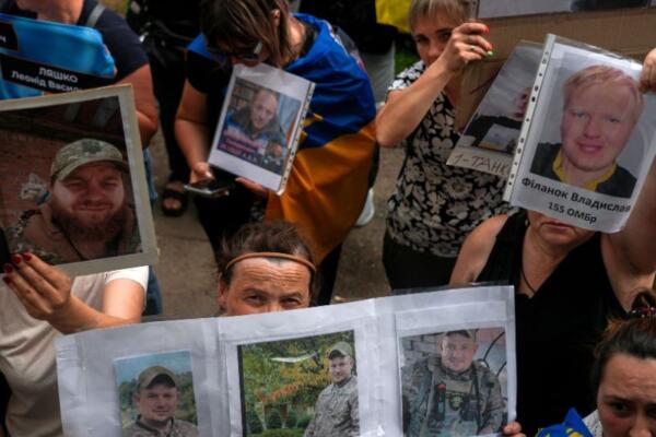 La gente muestra fotografías de sus familiares y amigos desaparecidos a los prisioneros de guerra ucranianos. AFP
