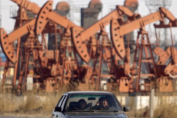 Fotografía de archivo que muestra un automóvil que circula junto a una plataforma petrolífera en el noreste de China.