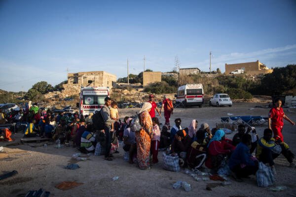 (FILES) Migrants gather outside the operational center called 