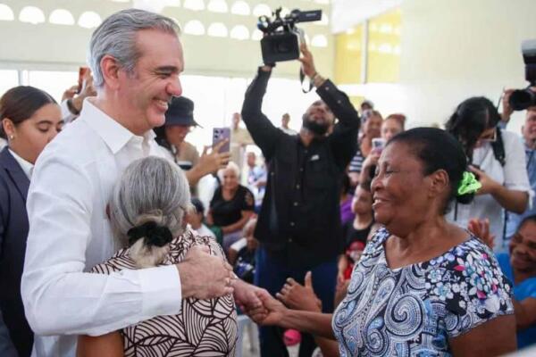 El presidente Luis Abinader abraza a dos mujeres durante una actividad