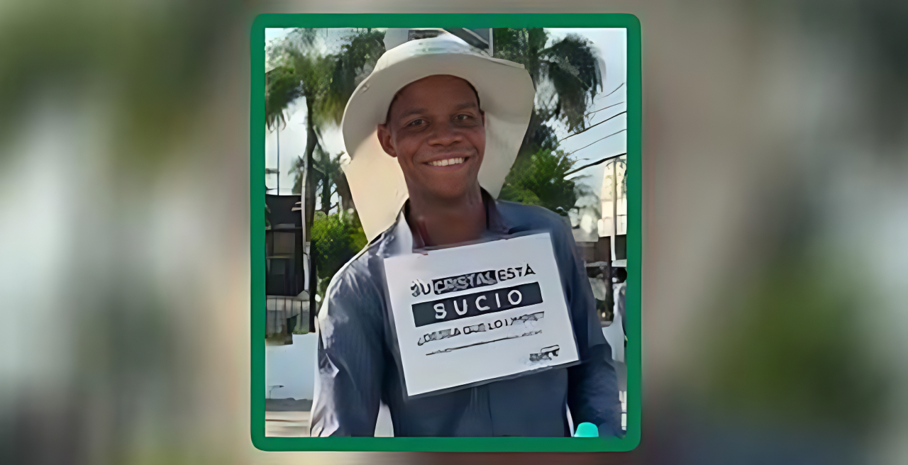 Joven limpia vidrios en Santo Domingo con letrero ofreciendo su servicio