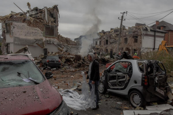 A man prepares to cover a damaged car with a plastic sheet at the site of heavily damaged residential buildings following a Russian air attack on the outskirts of Kyiv, on September 28, 2025, amid the Russian invasion of Ukraine. An overnight Russian barrage on Kyiv killed at least four people, including a 12-year-old girl, Ukrainian authorities said on September 28, 2025. (Photo by Roman PILIPEY / AFP)