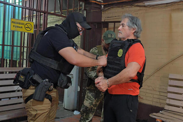 Fotografía cedida por la Secretaría Nacional Antidrogas de Paraguay que muestra el traslado del presunto líder del grupo criminal La Barredora, Hernán Bermúdez Requena (d), hacia el Aeropuerto Internacional Silvio Pettirossi en Asunción (Paraguay). EFE/ 