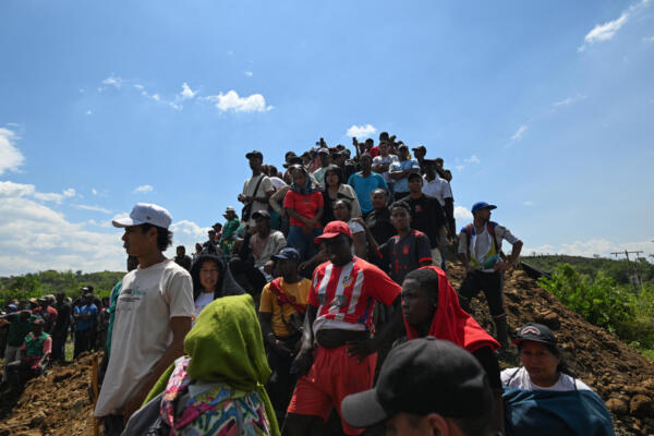 People look at an excavator working at the site where an illegal gold mine collapsed with seven miners trapped in Santander de Quilichao, department of Cauca, Colombia, on September 12, 2025. Seven miners are trapped at an illegal gold mining site in southwestern Colombia, apparently due to a cave-in, the state-run National Mining Agency (ANM) reported on Friday. (Photo by Joaquin SARMIENTO / AFP)