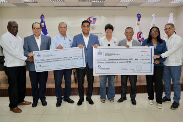 El ministro de Deportes, Kelvin Cruz, entrega de manera simbólica los cheques al presidente del COD, Garibaldy Bautista. En la gráfica, funcionarios de Deportes y directivos de la entidad olímpica.