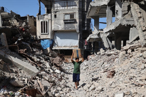 Un niño palestino lleva una caja de suministros de emergencia proporcionada por el Programa Mundial de Alimentos (PMA) tras recibirla de un punto de distribución de ayuda en el campo de refugiados de Nuseirat, en el centro de la Franja de Gaza, el 19 de octubre de 2025. (Foto de Eyad BABA / AFP)