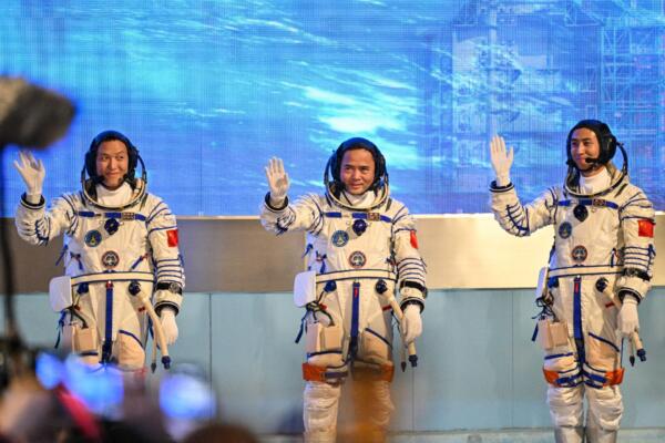 Los astronautas de la misión espacial china Shenzhou-21, Zhang Hongzhang (izq.), el comandante Zhang Lu (centro) y Wu Fei (der.), saludan durante una ceremonia de despedida antes de abordar un autobús que los llevará a la nave espacial Shenzhou-21 en el Centro de Lanzamiento de Satélites de Jiuquan, en el desierto de Gobi, al noroeste de China, el 31 de octubre de 2025. (Foto de Hector RETAMAL / AFP)
