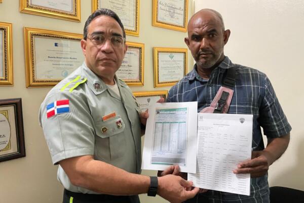 El coronel Rafael Tejeda Baldera y Ector de León Sánchez se abrazan tras resolver el caso de las multas en la sede de la DIGESETT en Nagua.